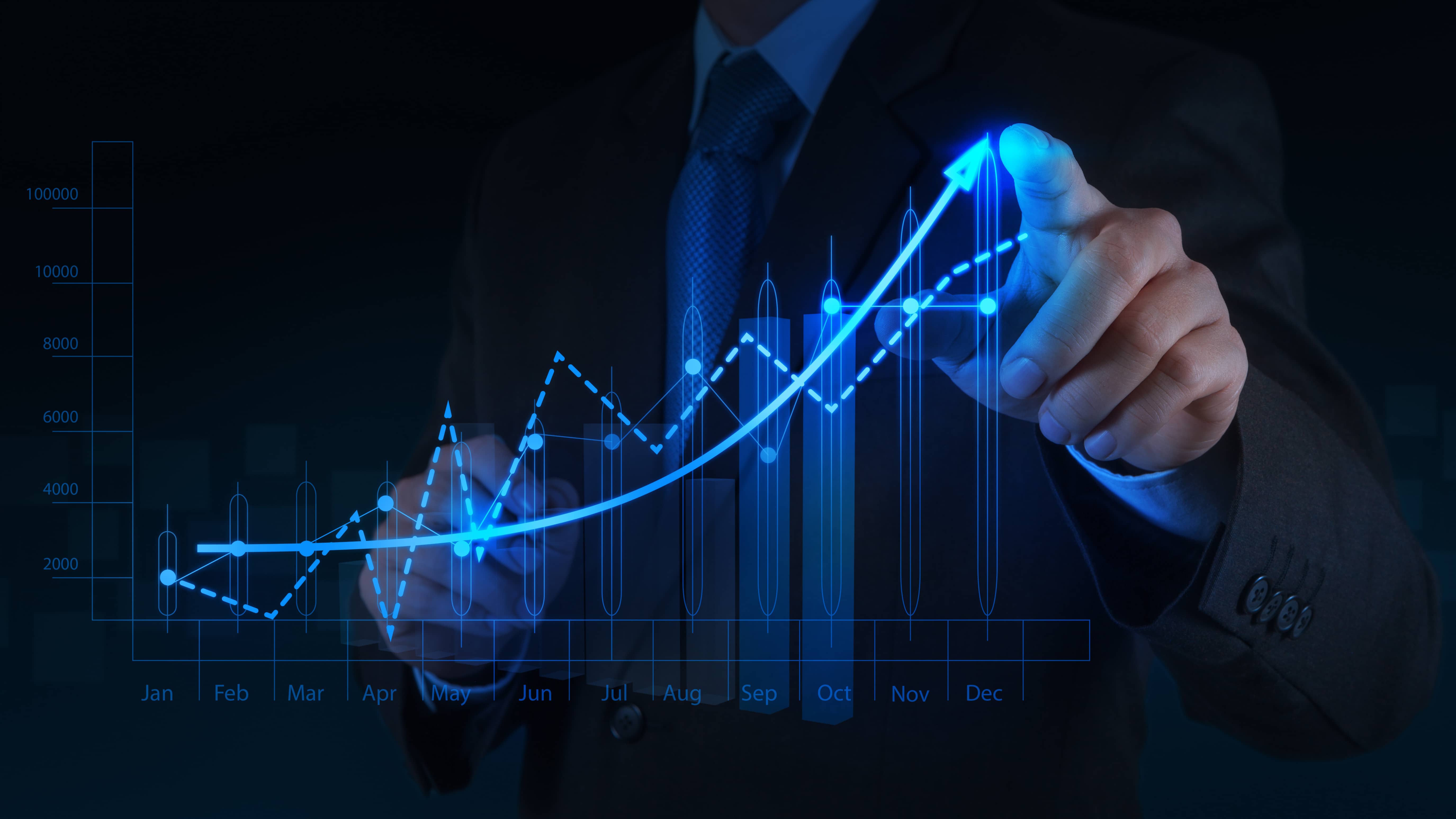 A businessman in a dark suit is pointing at a glowing blue graph with his finger, representing the continuous monitoring and auditing processes to ensure ongoing regulatory adherence.