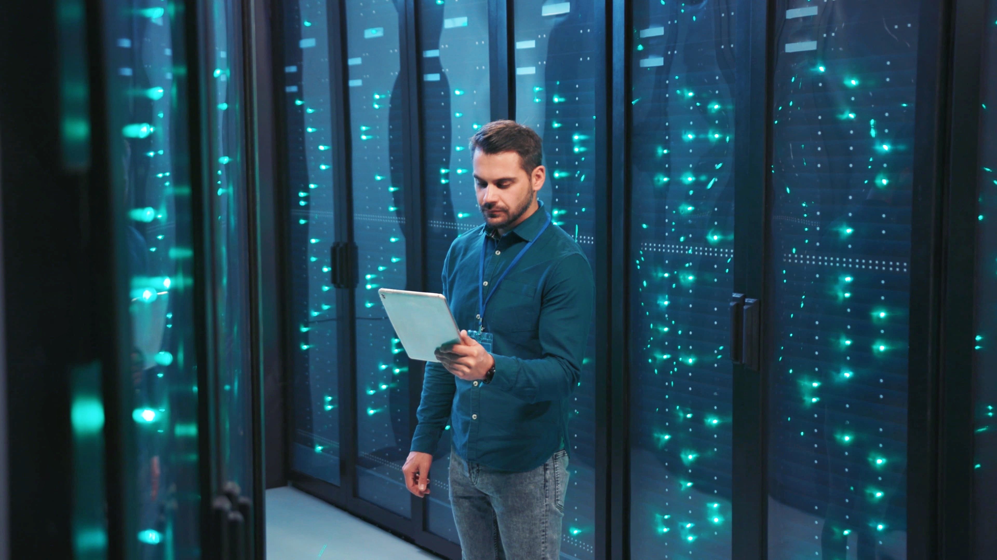 An IT professional looking at a tablet in a datacenter, ensuring optimal network performance