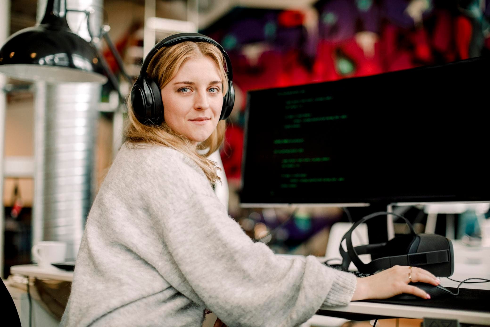 A blonde woman wearing headphones sits at her desk and looks at the camera, representing the team of experts at Fast Fixx who are dedicated to helping businesses comply with the GDPR and protect the personal data of EU citizens.