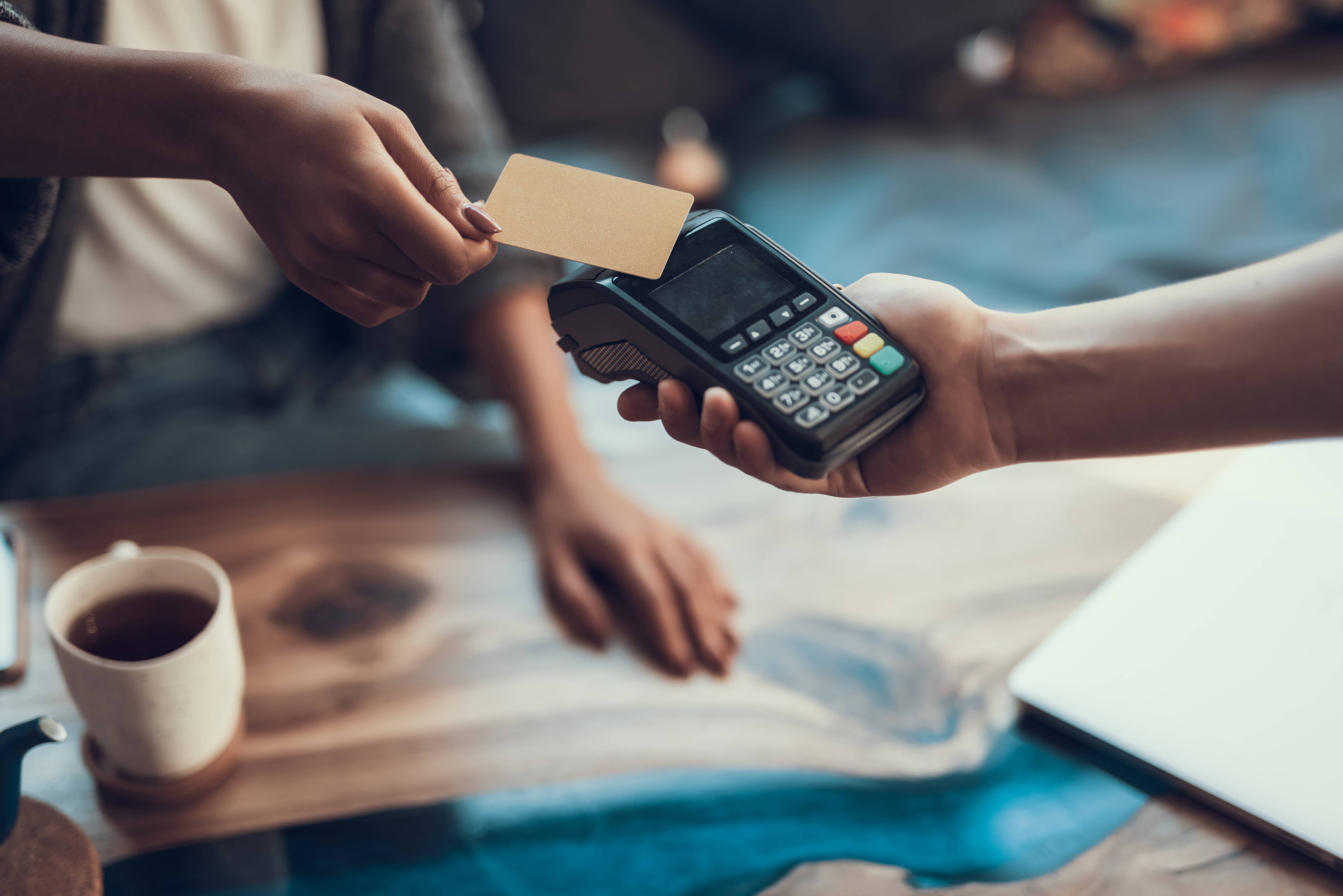 A customer paying with a credit card at a point-of-sale terminal, symbolizing the need for businesses to achieve and maintain PCI DSS compliance to protect cardholder data