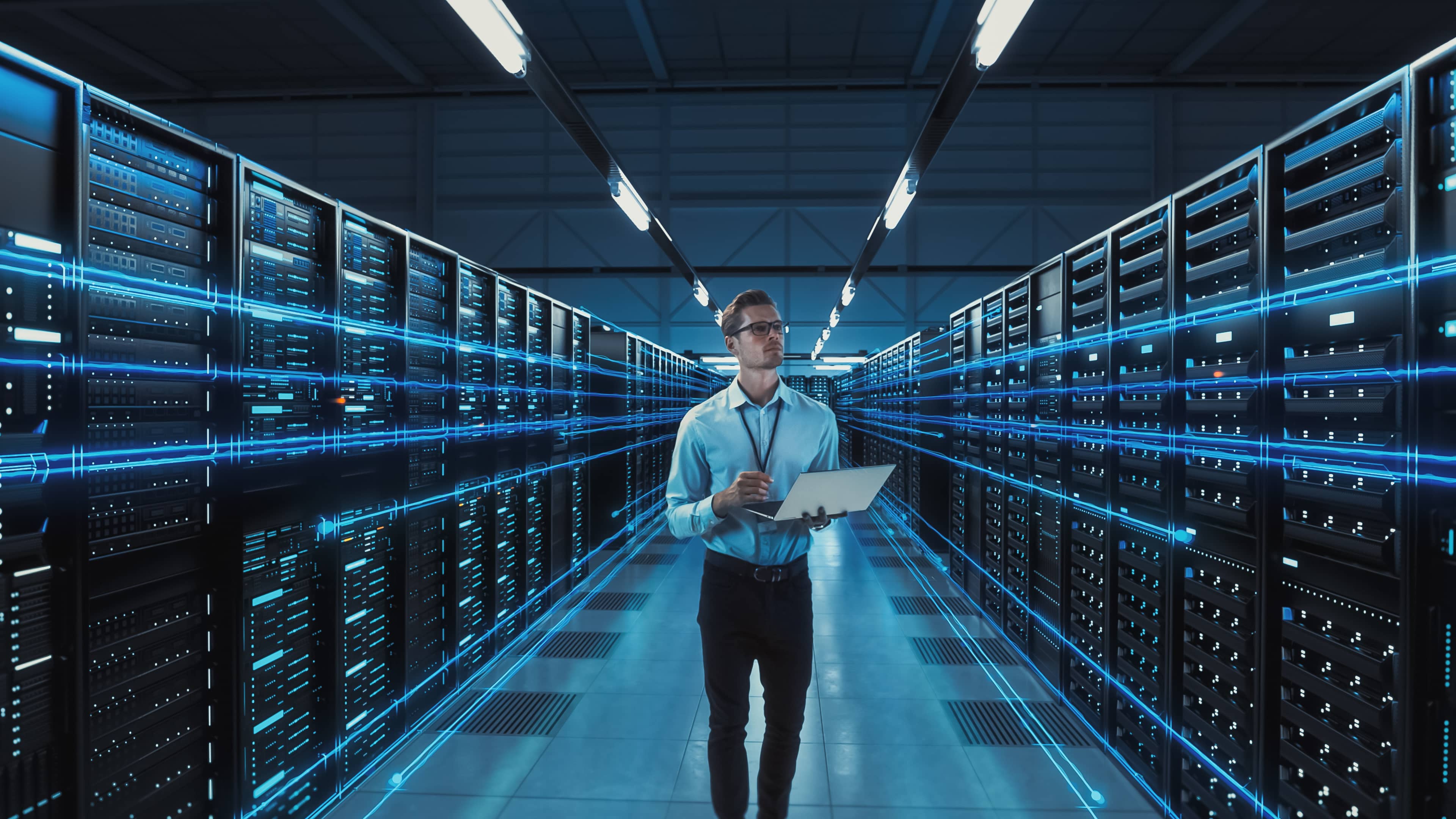 IT professional walking through a data center with rows of servers, representing the cloud compliance services offered by Fast Fixx to ensure cloud environments meet regulatory and security requirements