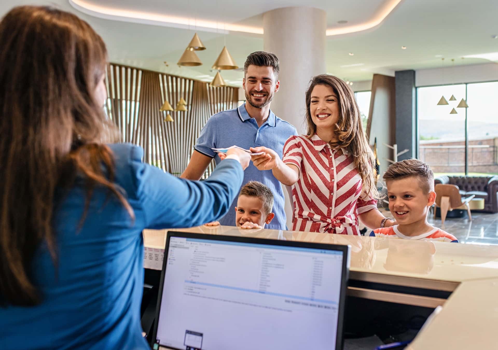 A family checking in to a hotel, representing the retail and hospitality industry, where Fast Fixx offers IT solutions to streamline operations, enhance customer experience, and drive growth.
