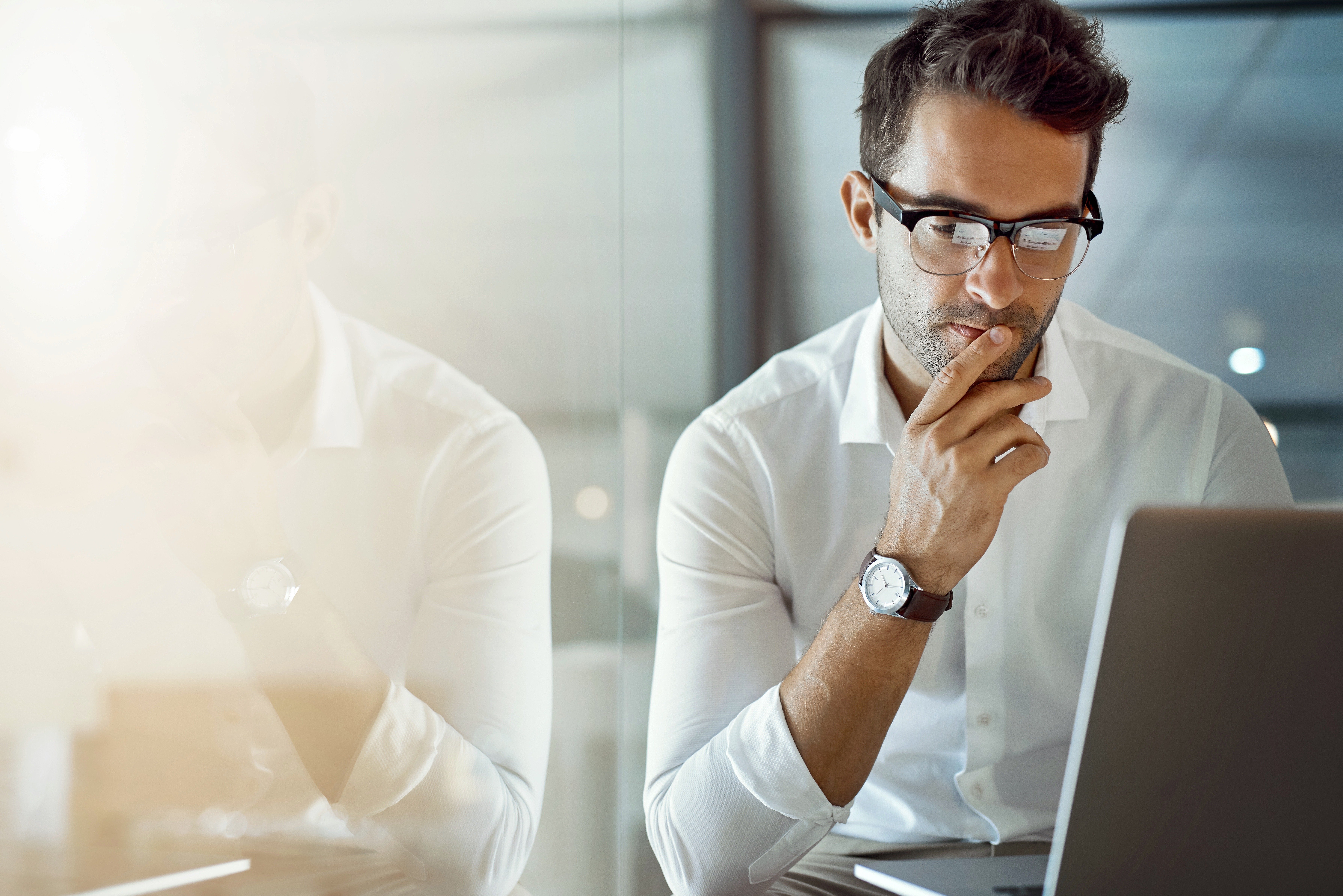 A man reading looking at a laptop, likely reading about IT best practices from Fast Fixx